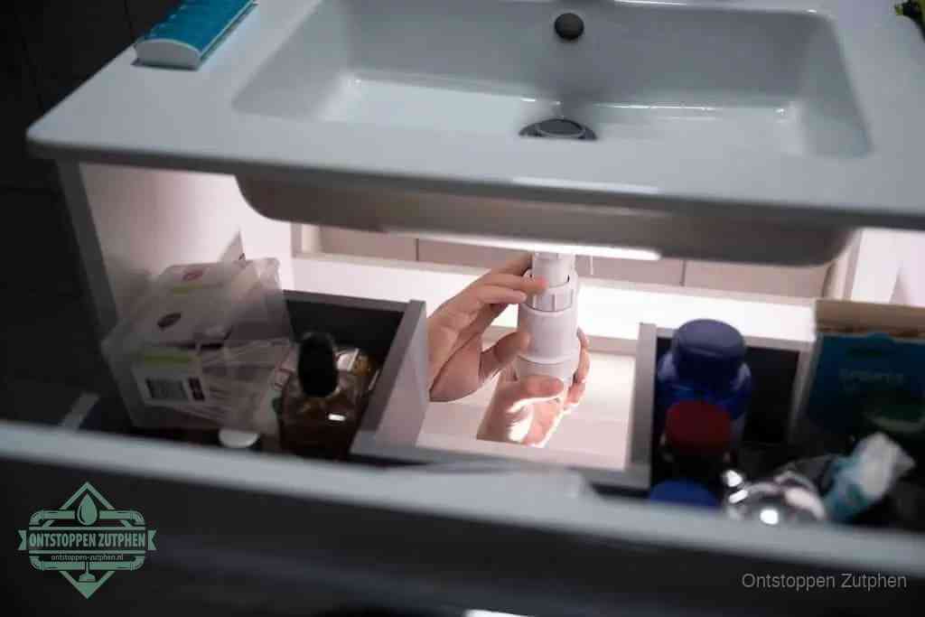 Een pompfles met zeep boven een wastafel, de heet water en afwasmiddel-methode om een vetprop in de afvoer los te maken in Zutphen