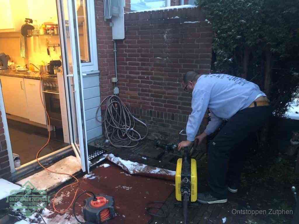 Een monteur werkt buiten bij een open riool-/grondput met een elektrische ontstoppingsmachine om een verborgen afvoerprobleem op te sporen in Zutphen