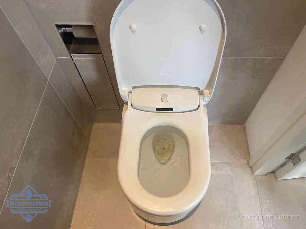 Een wit hangtoilet waarin een prop wc-papier op het water blijft drijven, een duidelijk signaal van een verstopte wc in Zutphen