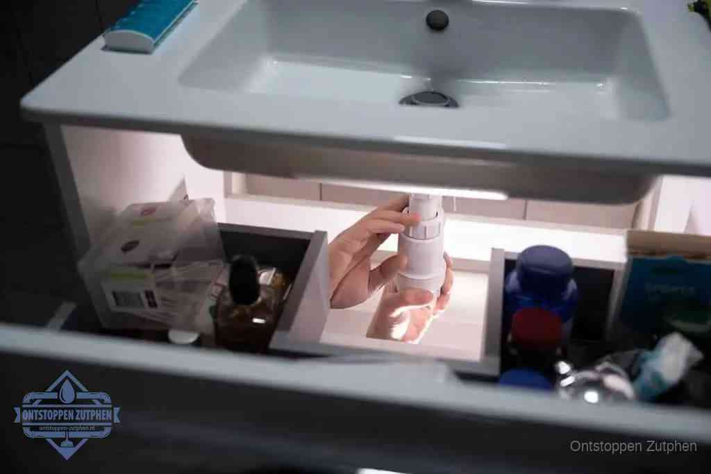 Een pompfles met zeep boven een wastafel in de toiletruimte, de warm water en afwasmiddel-methode om de wc te ontstoppen in Zutphen