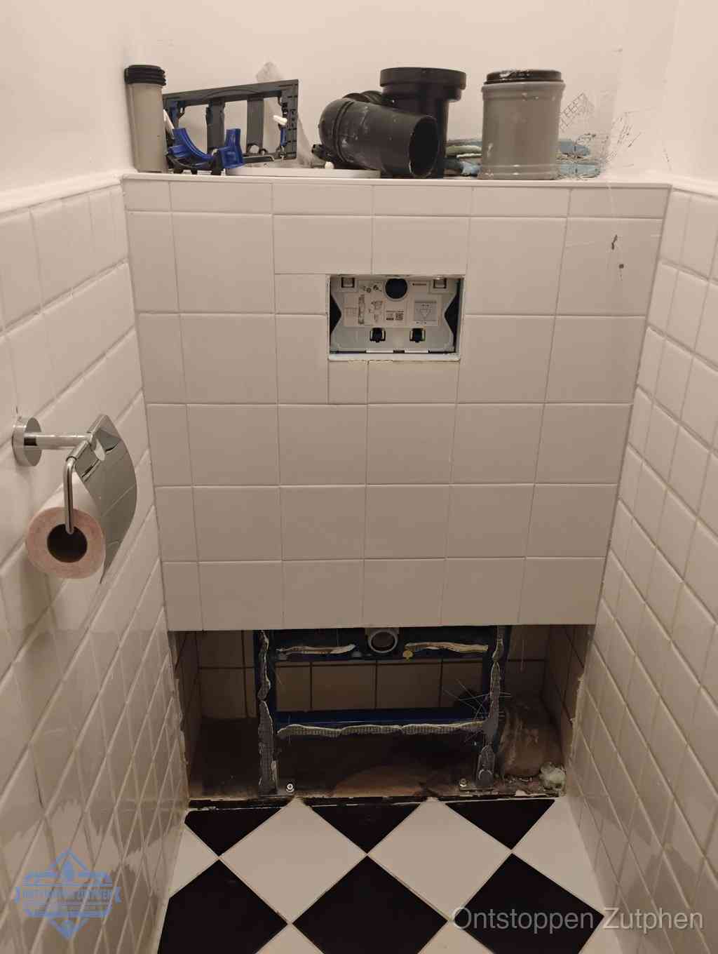 Een toiletruimte waar het hangtoilet en de inbouwreservoir-onderdelen zijn vrijgelegd voor onderhoud, periodiek nazicht voorkomt een wc-verstopping in Zutphen